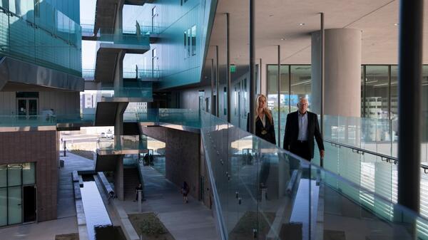 Rob and Melani Walton walk the exterior corridors of the Rob & Melani Walton Center for Planetary Health