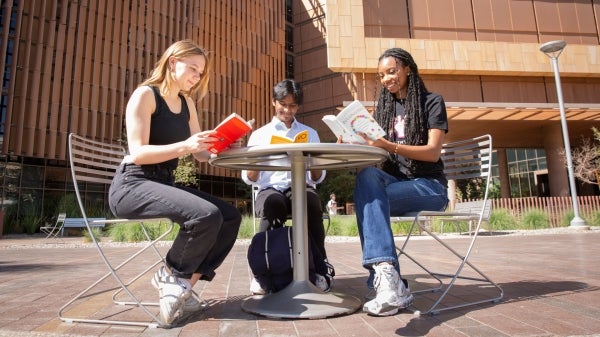 Three students in Arizona State Unviersity' Ira A. Fulton Schools of Engineering are pictured reading books outdoors on the ASU Tempe Campus