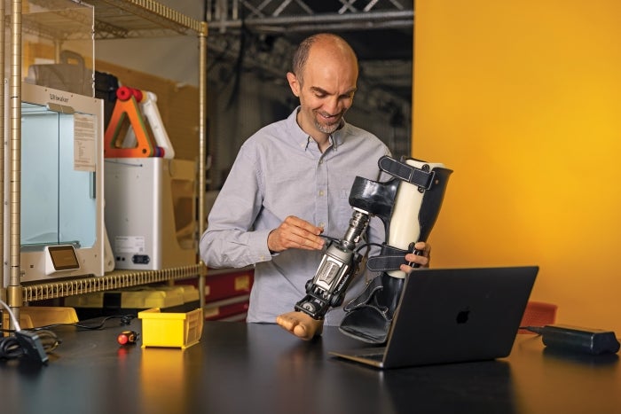 A man uses a tool to work on a prosthetic leg